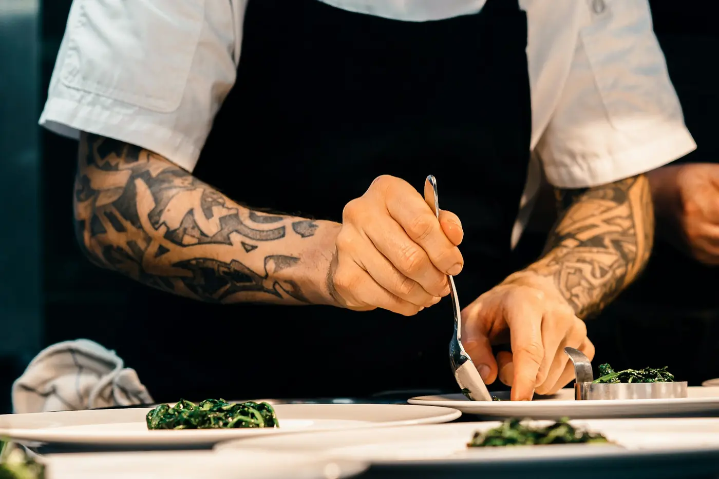 A chef plates a dish at the pass