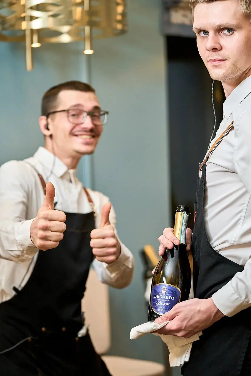 Two smiling servers, one giving a thumbs up